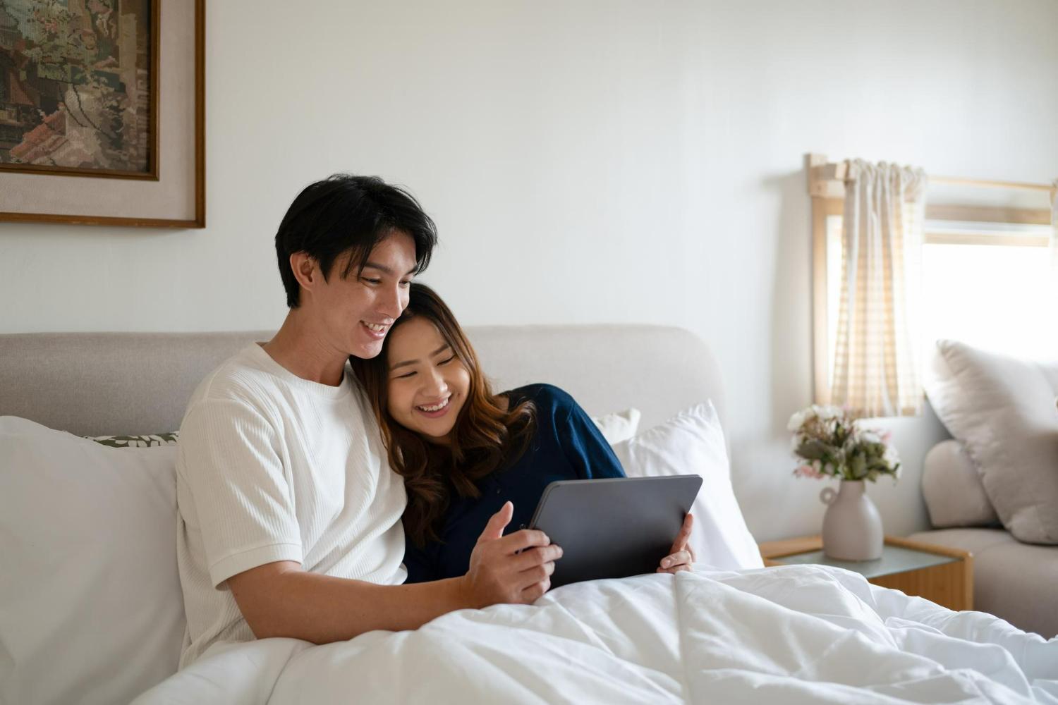 Mattresses for Couples: How to Choose the Right Mattress for Newlyweds 1 Young couple watching a show on a tablet while sharing a bed
