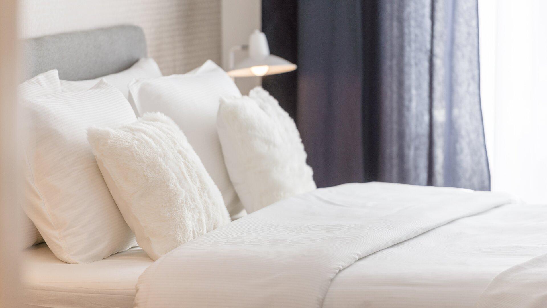 What Pillow Height Is Right for Your Sleeping Position? 1 White bed styled with multiple pillows, illustrating pillow loft and support options for different sleepers.