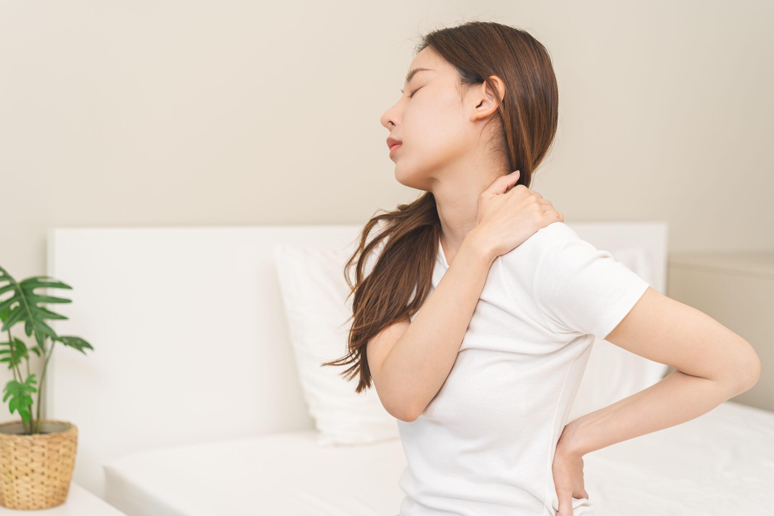 How Long Does A Mattress Last and When to Replace It 9 Woman waking with back pain and sitting on the edge of the bed, a common sign a mattress needs replacing